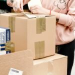Person sealing a cardboard box to ship an online order