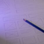 Hand-drawn website wireframes on dot grid paper with a pencil
